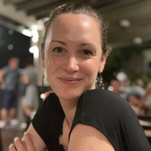 A picture of Katie looking directly at the camera, smiling and wearing a block shirt.